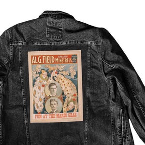 May include: A black denim jacket with a vintage poster patch on the back. The poster advertises the "Greater ALG. Field Minstrels" and features a group of performers in colourful costumes. The text on the poster reads "Fun at the Mardi Gras."