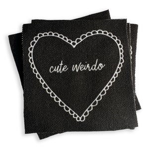 May include: Black fabric patch with a white heart outline and the text "cute weirdo" inside.