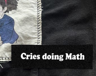May include: Black fabric patch with white text that reads "Cries doing Math".