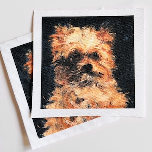 May include: Two square fabric patches with a dog portrait. The dog's fur is rendered in shades of brown and gold against a dark background. Each patch has a white border, and the image is a close-up of the dog's face.