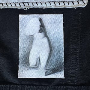 May include: A black and white photo of a person's torso, printed on a white fabric patch.