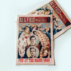 May include: Two vintage fabric patches featuring the text "ALG Field Minstrels" and images of clowns and performers. The patches have a cream-colored background with red and blue accents, and the phrase "Fun at the Mardi Gras".