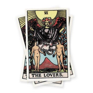 May include: The Lovers tarot card features a winged figure with a crown above two nude figures standing on either side of a mountain. The card is numbered VI and the text "THE LOVERS." is printed at the bottom.