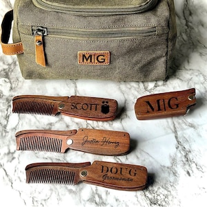 May include: Four personalized wooden pocket combs with engraved names, including "MIG", "SCOTT", "Justin Hong", and "DOUG Groomman". The combs are displayed on a white marble surface next to a green canvas zippered toiletry bag with a leather patch that reads "MIG".