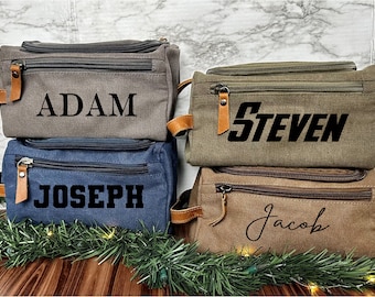 May include: Four personalized canvas toiletry bags stacked on top of each other. The bags are in different colors and have the names "Adam", "Steven", "Joseph", and "Jacob" printed on them.