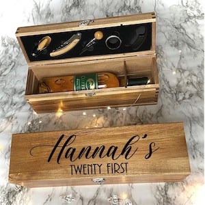 May include: Wooden box with a bottle of wine and a set of wine tools inside. The box is engraved with the text "Hannah's Twenty First".