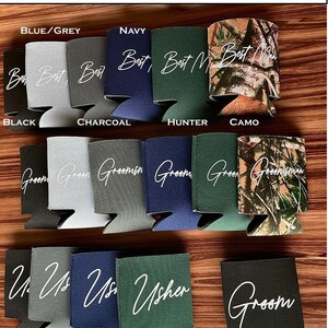 May include: A variety of can coolers in different colors and patterns, including black, gray, navy, green, and camo. The coolers feature different text, including "Groom", "Best Man", "Usher", and "Groomsman".