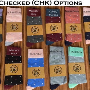 May include: A collection of patterned socks in various colors, including lilac, pink, maroon, cobalt, and navy. Each pair features a checked design and is labeled with color combinations. The socks are displayed on a wooden surface.