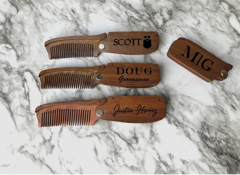 May include: Four wooden pocket combs with personalized engravings. The combs are brown and have a black engraved design. The names on the combs are Scott, Doug, Mig, and Justin Henry.