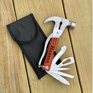 May include: A multi-tool hammer with a wooden handle engraved with the name "Hansen". The tool has a variety of blades and tools, including a saw, a knife, and a screwdriver. It comes with a black nylon carrying case.
