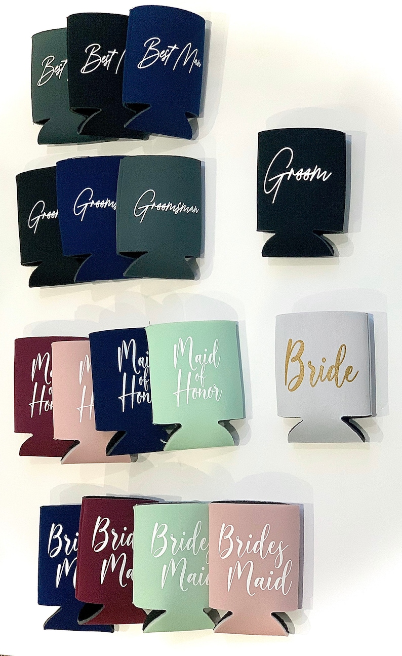 May include: Assortment of colorful can coolers with various wedding party titles printed in white and gold lettering. The titles include "Best Man", "Groom", "Groomsman", "Maid of Honor", "Bride", and "Bridesmaid".