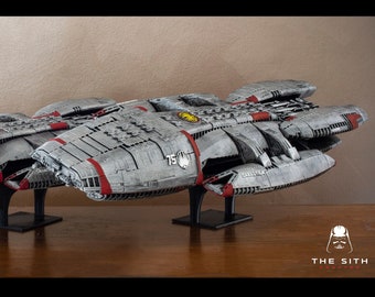 May include: Three grey and red spaceship models on display stands. The models are different sizes, with the largest model in the back and the smallest model in the front. The models are made of LEGO bricks and have a detailed design.