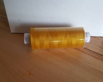 May include: A spool of gold thread with the text "TROJA Qual" on the label.