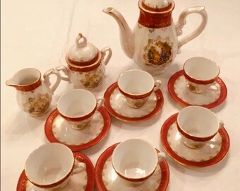 May include: A vintage porcelain tea set with a red and gold floral design. The set includes a teapot, creamer, sugar bowl, and six teacups and saucers.