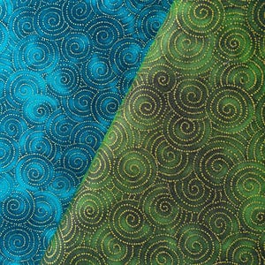 Op de afbeelding: Twee stukken stof met een herhalend spiraalpatroon. De ene is blauwgroen met gouden spiralen, de andere groen met gouden spiralen. De spiralen zijn gemaakt van kleine gouden stippen.