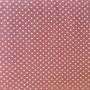 Pode incluir: Um close-up de um tecido rosa com um padrão de bolinhas brancas.