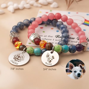 May include: Two beaded bracelets with personalized dog tags. One bracelet features blue and multicolored beads, the other pink. The tags are engraved with dog portraits and names, one reading "Oakley" and the other "Rocky". The Oakley tag is 7/8 inches, and the Rocky tag is 3/4 inches.