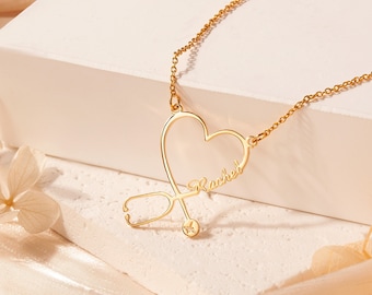 May include: Gold necklace with a heart-shaped pendant featuring a stethoscope and the name "Rachel".