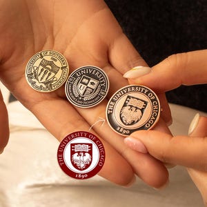 May include: Four different gold, silver, and bronze colored circular pins with university logos. The pins feature the University of Southern California, the University of Chicago, and the University of Illinois at Urbana-Champaign.