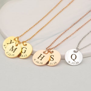 May include: Three gold necklaces with personalized disc pendants. The first necklace has three discs with the letters Y, M, and G, and the dates 8.5.21.12.15 and 10.15. The second necklace has two discs with the letters H and S, and the dates 9.10.18 and 1.11.19. The third necklace has one disc with the letter Q and the date 6.12.20.