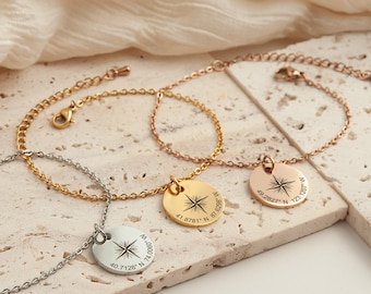 May include: Three gold, silver, and rose gold bracelets with compass charms. Each charm has a star and coordinates engraved on it. The coordinates are 40.7128°N 74.000, 41.8781°N 87.8708, and 49.2827" N 123.1207 W.