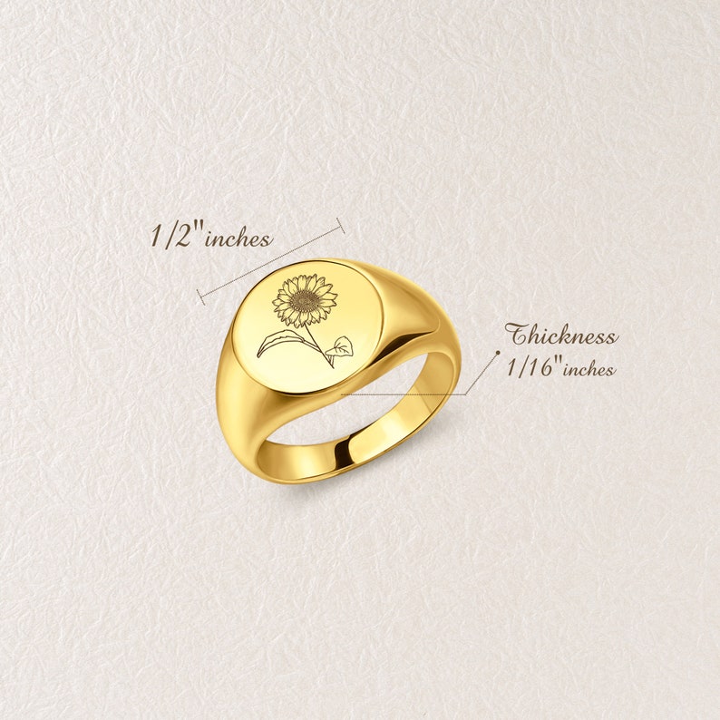May include: A gold signet ring with a sunflower design engraved on the top. The ring is 1/2" in diameter and 1/16" thick.