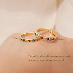 May include: Two gold rings featuring multi-colored gemstones. One ring is 2mm wide, the other is 2.8mm wide and engraved with the text "You Are My Sunshine, Mom". Text on the image states wide bands can be engraved, narrow cannot.
