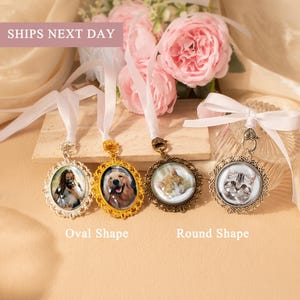 May include: Ornate photo pendants with images of pets, including a dog and cats. The pendants are in oval and round shapes, with decorative frames and white ribbon for hanging. The text "SHIPS NEXT DAY" is visible.