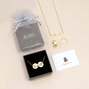 May include: A gold necklace with two round pendants featuring engraved pet portraits. The necklace is displayed in a gray box with a white card that reads "A gift for you".