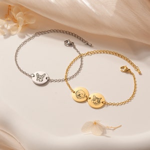 May include: Two personalized pet photo bracelets. One bracelet is silver with a single oval charm featuring a dog's face. The other bracelet is gold with two round charms featuring a dog and a cat's face.