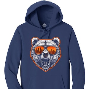May include: A navy blue hooded sweatshirt with a graphic of a bear wearing sunglasses. The sunglasses reflect a cityscape with orange and yellow buildings.