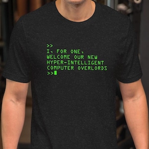 Puede incluir: Camiseta gris oscuro con texto verde: "I, FOR ONE, WELCOME OUR NEW HYPER-INTELLIGENT COMPUTER OVERLORDS". La camiseta de manga corta tiene cuello redondo.