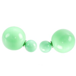 Puede incluir: Un par de pendientes verdes de doble cara con una bola redonda más grande en un lado y una bola redonda más pequeña en el otro.