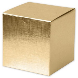 Puede incluir: Una caja de regalo dorada y cuadrada con un patrón texturizado de trama cruzada en la parte superior y frontal. La caja tiene un diseño sencillo y limpio con una tapa que se pliega sobre la parte superior. La caja es de material brillante.