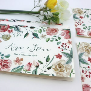 May include: Save the Date cards with a floral design featuring pink, red, and white flowers. The text on the card reads "Save the Date" and "Kira + Steve" with the date "20th September 2019".