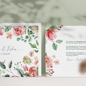 May include: A wedding invitation featuring a floral border in shades of pink, green, and white. The text reads "Anna & Sorben" and "27. August 2021". The reverse side of the invitation provides details about the wedding ceremony and reception.