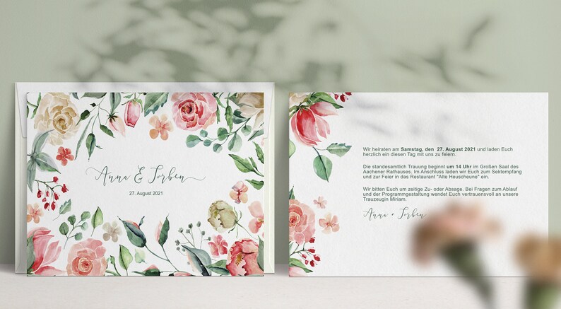 May include: A wedding invitation featuring a floral border in shades of pink, green, and white. The text reads "Anna & Sorben" and "27. August 2021". The reverse side of the invitation provides details about the wedding ceremony and reception.