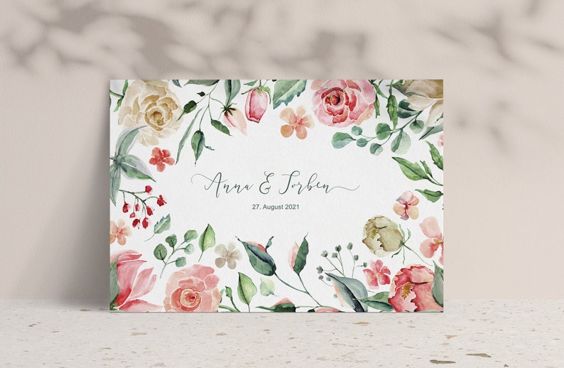 May include: A watercolour wedding invitation with a floral border. The invitation features pink, white and green flowers and leaves. The text on the invitation reads "Anna & Torben" and "27 August 2021".