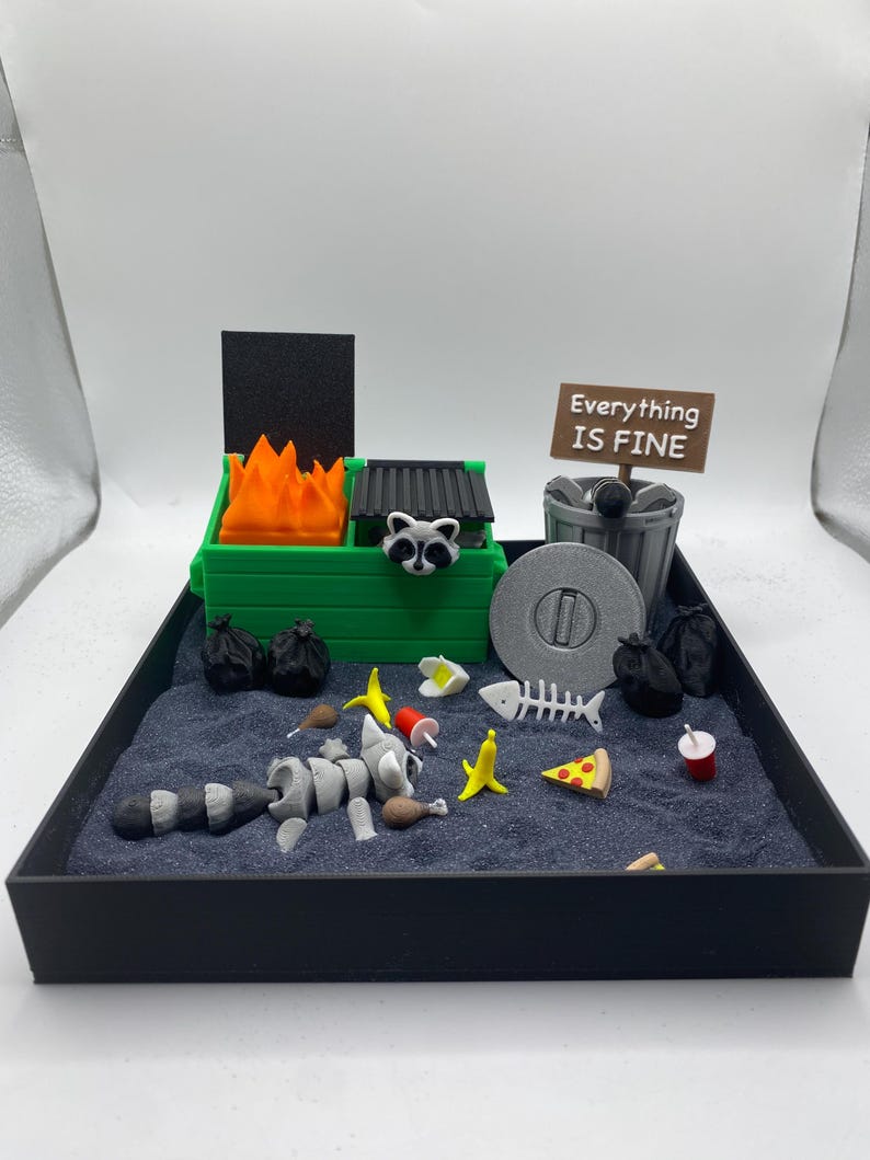May include: A miniature diorama featuring a raccoon skeleton amidst trash, a green dumpster with flames, and a sign that reads "Everything Is Fine." Includes a pizza slice, bananas, and a fish skeleton.