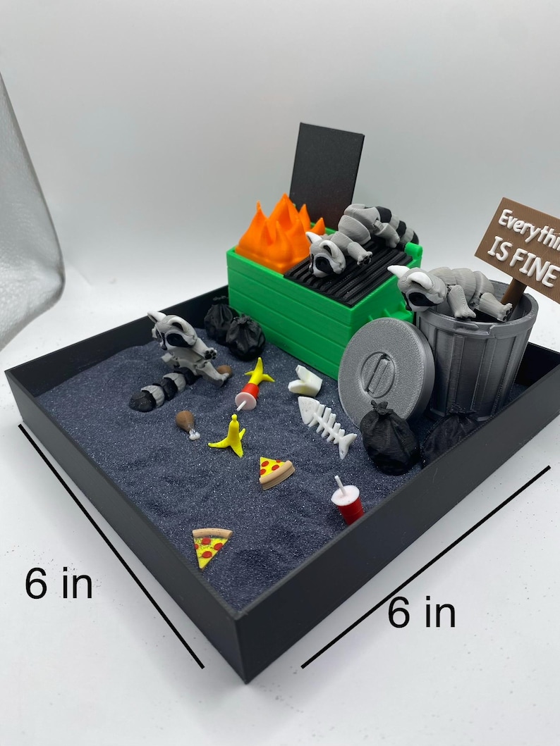May include: A miniature diorama scene in a 6-inch square black tray. The scene includes a green grill with orange flames, raccoons, a trash can, and scattered food items. A sign reads "Everything is Fine."