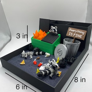 May include: A miniature diorama featuring a black tray (8 in x 6 in x 3 in) with a trash-themed scene. Includes a green dumpster with flames, raccoons, trash bags, and a sign that reads "Everything Is Fine."