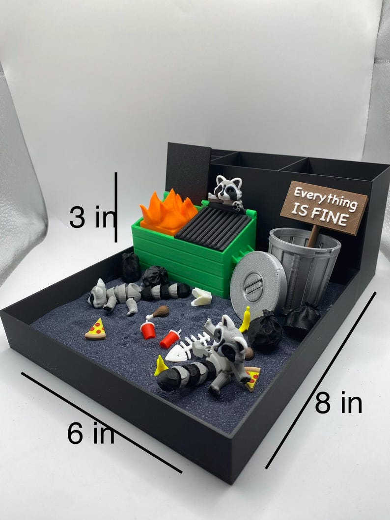 May include: A miniature diorama featuring a black tray (8 in x 6 in x 3 in) with a trash-themed scene. Includes a green dumpster with flames, raccoons, trash bags, and a sign that reads "Everything Is Fine."