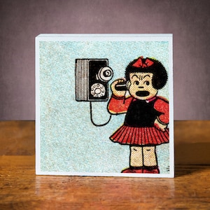 Op de afbeelding: Een vintage stripboekillustratie van een meisje met een rode jurk en zwart haar dat aan een draaischijftelefoon praat. De telefoon is aan een muur bevestigd en heeft een zwart-wit ontwerp.