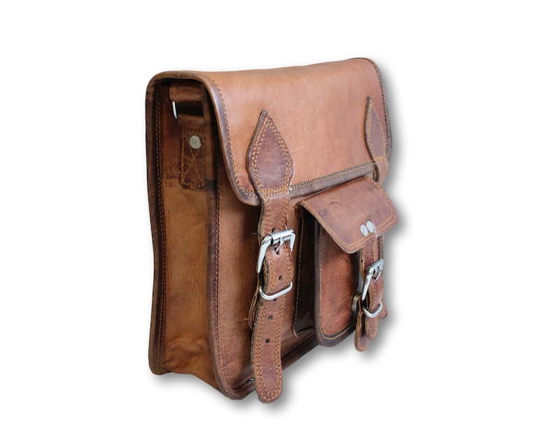 May include: A brown leather messenger bag with two buckles and a flap pocket. The bag has a strap and a small pocket on the front.