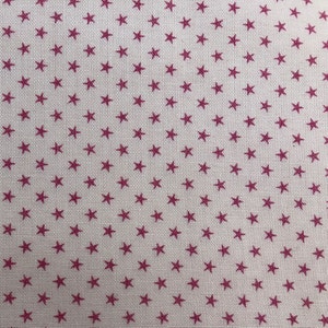 Peut inclure: Un tissu blanc avec un motif répétitif de petites étoiles rouge foncé.