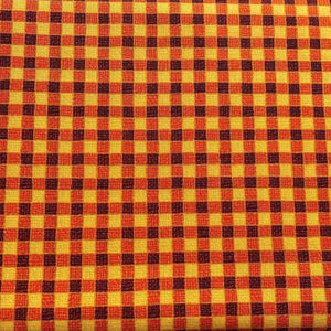 Pode incluir: Um tecido entrelaçado com um padrão xadrez vichy repetitivo em tons vibrantes de amarelo, laranja e castanho escuro. O têxtil apresenta uma grelha consistente de pequenos quadrados, criando um design de tabuleiro uniforme e denso.
