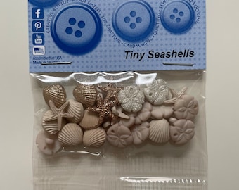 Może przedstawiać: Torebka z małymi guzikami w kształcie muszelek w kolorze białym, różowym i złotym. Torebka jest oznaczona jako "Tiny Seashells" i jest przeznaczona do rękodzieła, tworzenia kartek, pikowania, szycia i scrapbookingu.