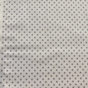 Può includere: Primo piano di un tessuto beige con un motivo ripetitivo di piccole stelle grigie scure.