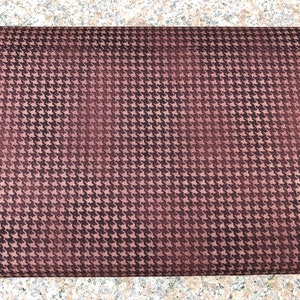 Könnte beinhalten: Nahaufnahme eines braunen Stoffes mit einem schwarzen Hahnentrittmuster.