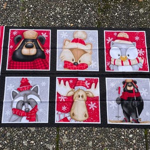 Könnte beinhalten: Stoffpaneel mit sechs Quadraten, die Wintertierillustrationen zeigen. Die Tiere, darunter ein Bär, Fuchs, Eule, Waschbär, Elch und ein weiterer Bär, tragen Wintermützen und Schals. Der Hintergrund ist rot mit Schneeflocken.